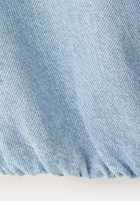 Tissu en denim bleu clair avec texture de tissage diagonal visible et bord élastique froncé en bas.