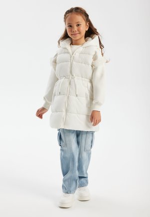Gilet imbottito bianco con chiusura a zip, vita elastica e cappuccio. Abbinato a jeans larghi blu chiaro e sneaker bianche. Semplice design del colletto.