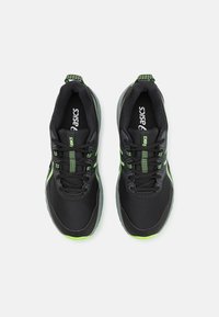Zapatillas deportivas negras con acentos verdes. Fabricadas con materiales de malla y sintéticos. Presentan una suela texturizada y un diseño con cordones para un ajuste seguro.
