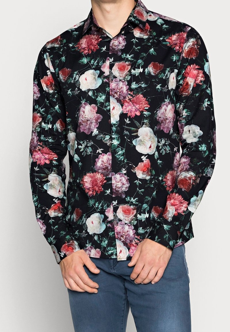 Camicia a bottoni floreale con sfondo scuro, fiori vivaci rosa, bianchi e rossi, colletto standard e maniche lunghe.