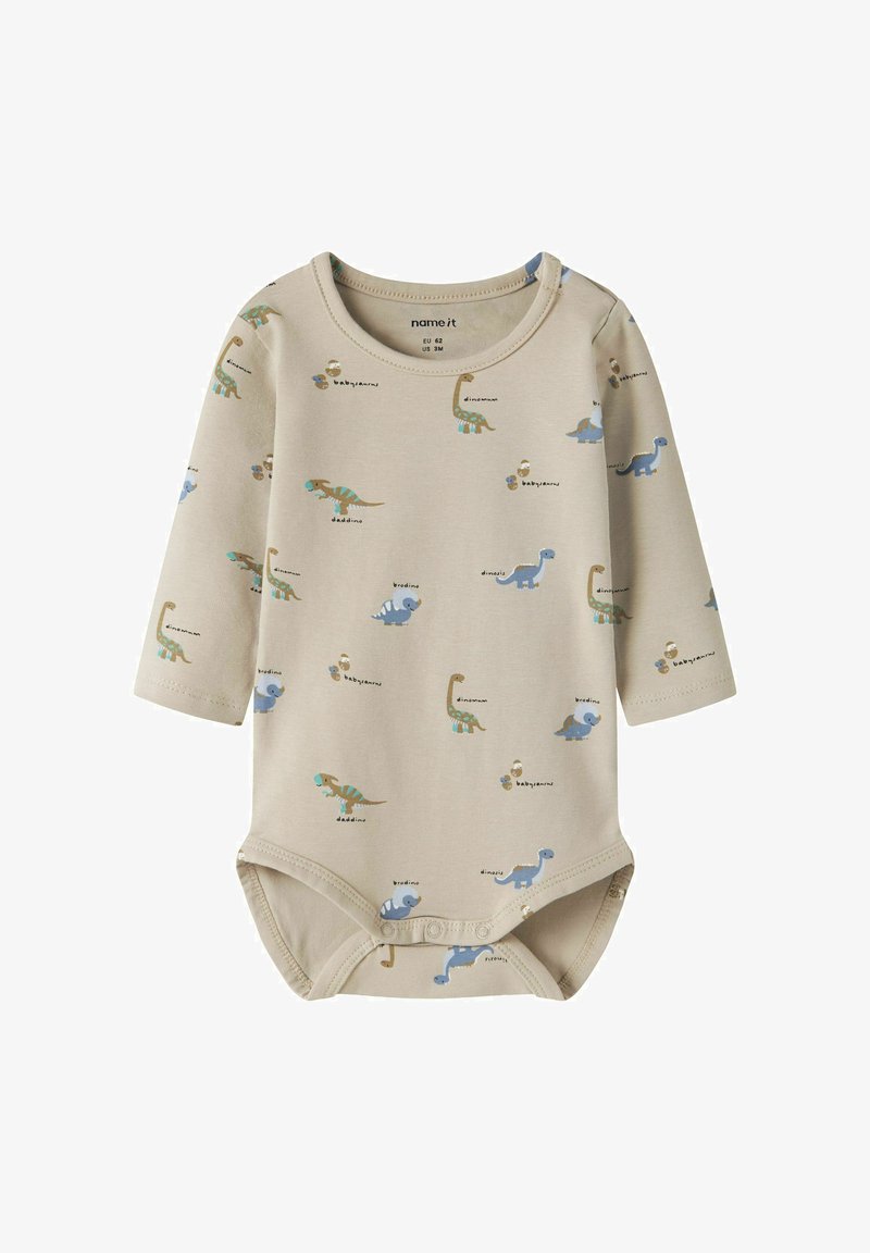 Body bébé beige à manches longues avec des dinosaures dessinés en bleu et vert et des boutons-pression à l'entrejambe.