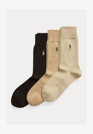 Tre par vikta crew-strumpor i mörkbrunt, beige och ljusbeige, var och en med en liten broderad polo-spelarlogotyp på sidan.