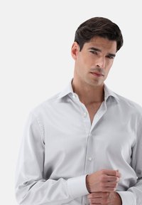 Hemd mit hellgrau-weißer vertikaler Streifenmusterung, aus glattem Stoff, mit klassischem Kragen und geknöpften Manschetten.