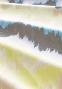 Tissu avec un mélange de motifs abstraits beige, jaune, bleu et gris, présentant une surface lisse et légèrement texturée.