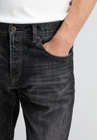 Donkerdenim jeans met een lichte vervaging, voorzien van een vijf-pocket ontwerp, een sluiting met een bovenste knoop, en contrasterende gele stiksels.