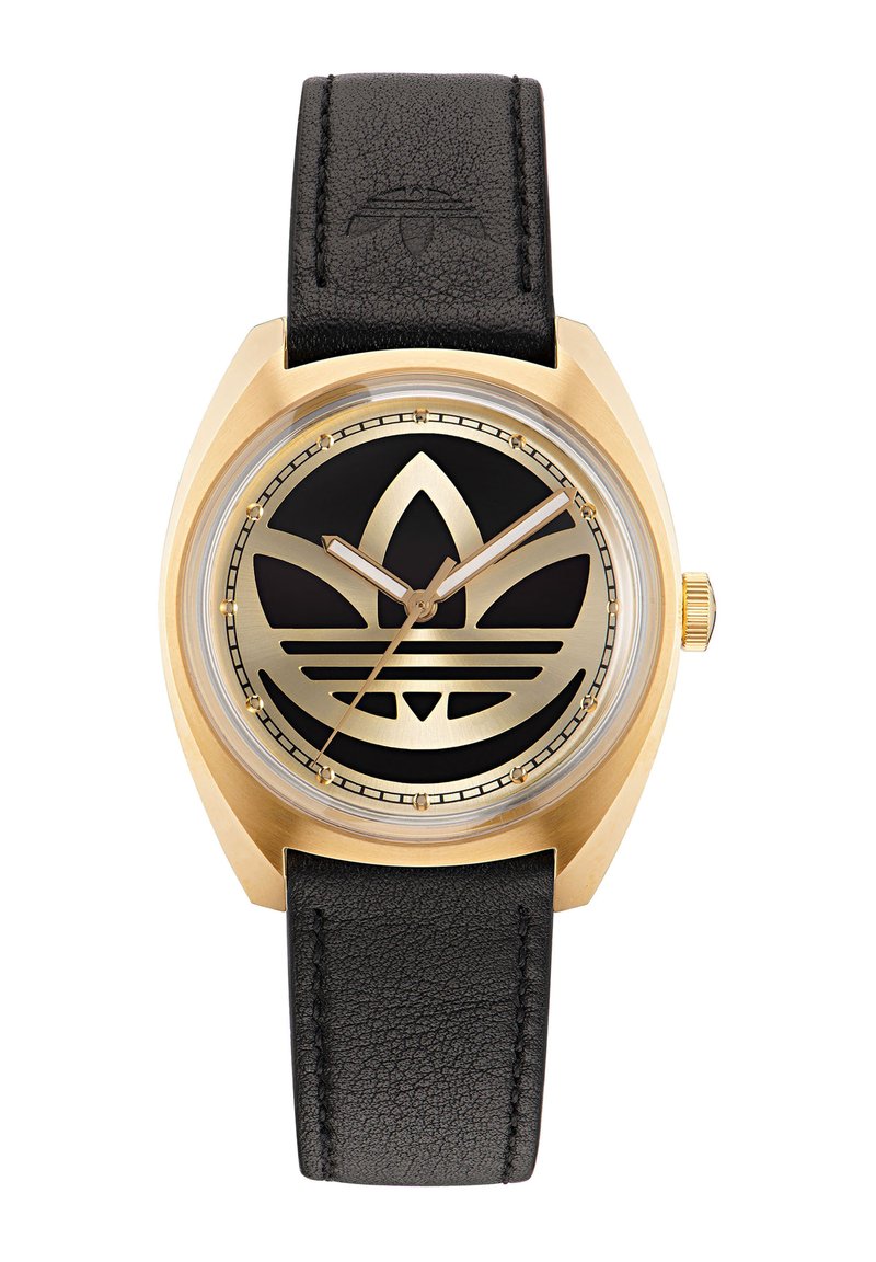 Kuldse tooniga kell musta näo ja silmapaistva logo kujundusega. Must nahkrihm tekstureeritud pinnaga. Selge kaitsev klaasilääts.