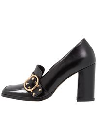 Chaussure à talon haut en cuir verni noir, avec un bout arrondi, ornée d'une boucle décorative et d'accents à clous sur un large talon bloc.