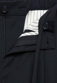 Schwarze maßgeschneiderte Hose mit Knopfverschluss, Reißverschluss und gestreiftem Innenfutter. Verfügt über eine glatte Textur und eine taillierte Passform.