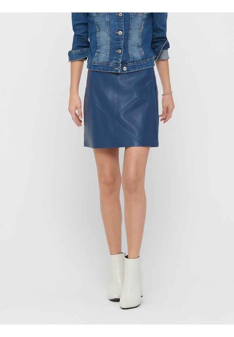 Jupe en cuir bleue au design ajusté avec des détails de couture diagonaux, associée à des bottines blanches et à une veste en denim. Texture lisse.