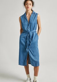 Robe en jean à design sans manches, col, boutons sur le devant et taille nouée. Longueur complète avec fentes latérales et délavage clair.