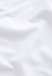 Tissu blanc doux avec de légères plis et des ombres subtiles, mettant en valeur sa texture lisse et son apparence propre.