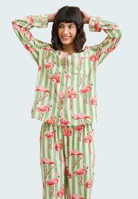 Ensemble de pyjama à motif flamant rose avec un design rayé vert et blanc, manches courtes et pantalon avec une taille élastique.