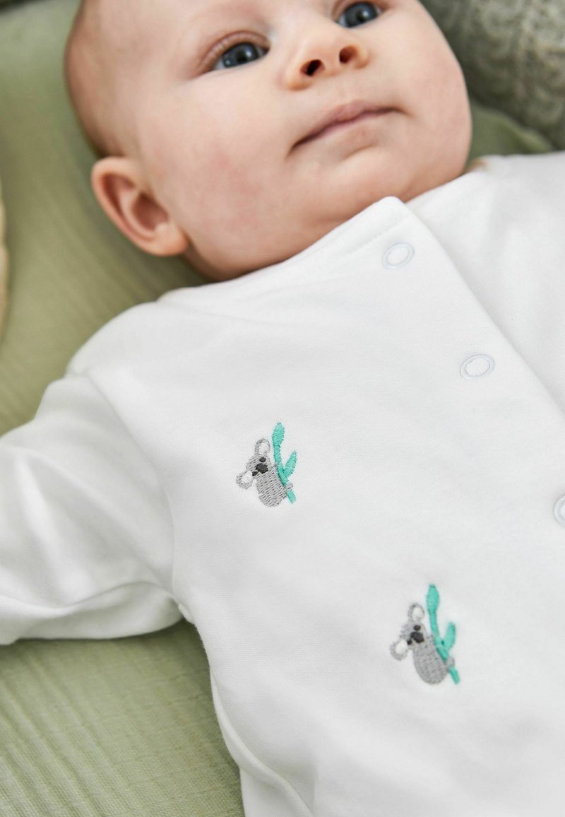 Weißer Baby-Body mit grauem Koala und grüner Blattstickerei. Weicher Stoff, mit Druckknöpfen an der Seite für einfaches Ankleiden.