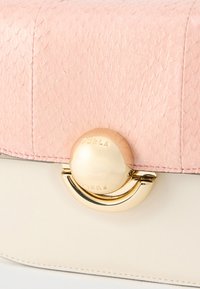 Ροζ τσάντα από ανάγλυφο δέρμα με χρυσό μεταλλικό κούμπωμα και λείο μπεζ σώμα. Διαθέτει κυκλικό χρυσό στολίδι με εγχάρακτο λογότυπο της μάρκας.