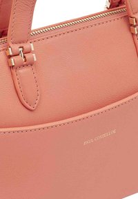 Roze leren handtas met een ritsluiting, goudkleurige hardware en een reliëf merknaam. Glad textuur met een gestructureerd ontwerp.