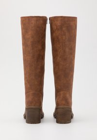 Wysokie brązowe botki z faux skóry o gładkiej fakturze, z zamkami błyskawicznymi na cholewce i drewnianymi obcasami na słupku. Prosty, klasyczny design.