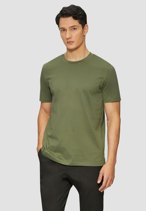 Olijfgroene katoenen T-shirt met een ronde halslijn en korte mouwen, ongekleed weergegeven over zwarte broeken. Zachte textuur, minimalistisch ontwerp.