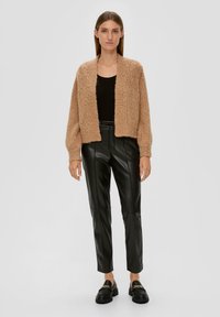 Hellbrauner Strickcardigan mit lockerer Passform, strukturiertem Stoff und offenem Vorderteil, kombiniert mit schwarzen Lederhosen und schwarzen Loafers.