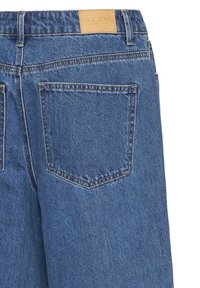 Jean en denim bleu moyen avec une étiquette en cuir portant l'inscription "PULZ JEANS". Comprend deux poches arrière avec des coutures contrastantes.
