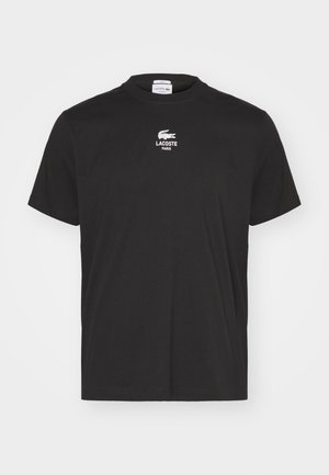 Juodas medvilninis marškinėliai su rifliuota apykakle, trumpomis rankovėmis ir mažu baltu išsiuvinėtu "Lacoste" logotipu virš "PARIS" krūtinėje.