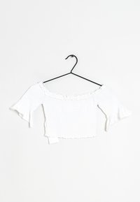 Weißes, schulterfreies Crop-Top mit geraffter Textur, Rüschensaum und ausladenden Ärmeln, auf einem schwarzen Kleiderbügel präsentiert.