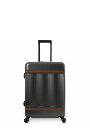 Musta kovakuorinen matkalaukku pystysuorilla urilla, ruskeilla vaakasuorilla hihnoilla, neljällä pyörällä ja pidennetyllä teleskooppikahvalla.