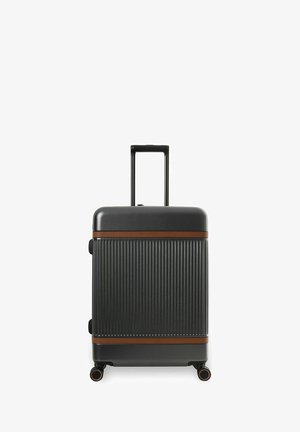 Zwarte harde koffer met verticale ribbels, bruine horizontale banden, vier wielen en een uitgeschoven telescopische handgreep.