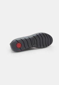 Sole di scarpa in gomma nera con un motivo di battistrada texture e un dettaglio centrale di ammortizzazione circolare rossa. Design durevole e flessibile.