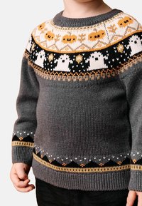 Pull gris en tricot présentant un motif coloré de fantôme et de citrouille sur le yoke, avec des accents noirs, orange et blancs. Poignets et ourlet côtelés.