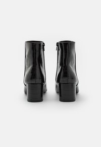 Czarne ankle boots ze wzmocnieniem w kształcie krokodyla, o gładkiej teksturze, okrągłym nosku i słupkowym obcasie. Posiadają zamek błyskawiczny z boku, co ułatwia zakładanie.