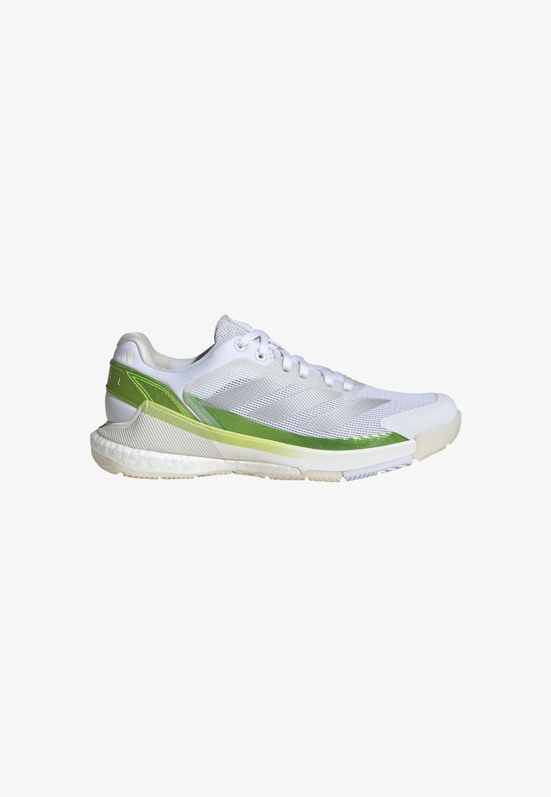 White athletic shoe with mesh upper, green accents, textured sole, and detailed stitching. Features a lace-up design and cushioned heel.