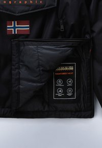 Schwarze Jacke mit norwegischem Flaggenpatch auf der Brust und Innenetikett, das wasserabweisende, winddichte, verklebte Nähte und atmungsaktive Stoffeigenschaften zeigt.