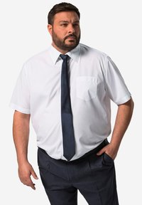 Camicia bianca a maniche corte con taschino, abbinata a una cravatta blu scuro e pantaloni eleganti blu navy. Tessuto morbido, design aderente.