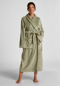 Strikket badekåpe i dempet grønn med teksturert overflate, lange ermer, sjalkrage, to frontlommer og matchende belte.
