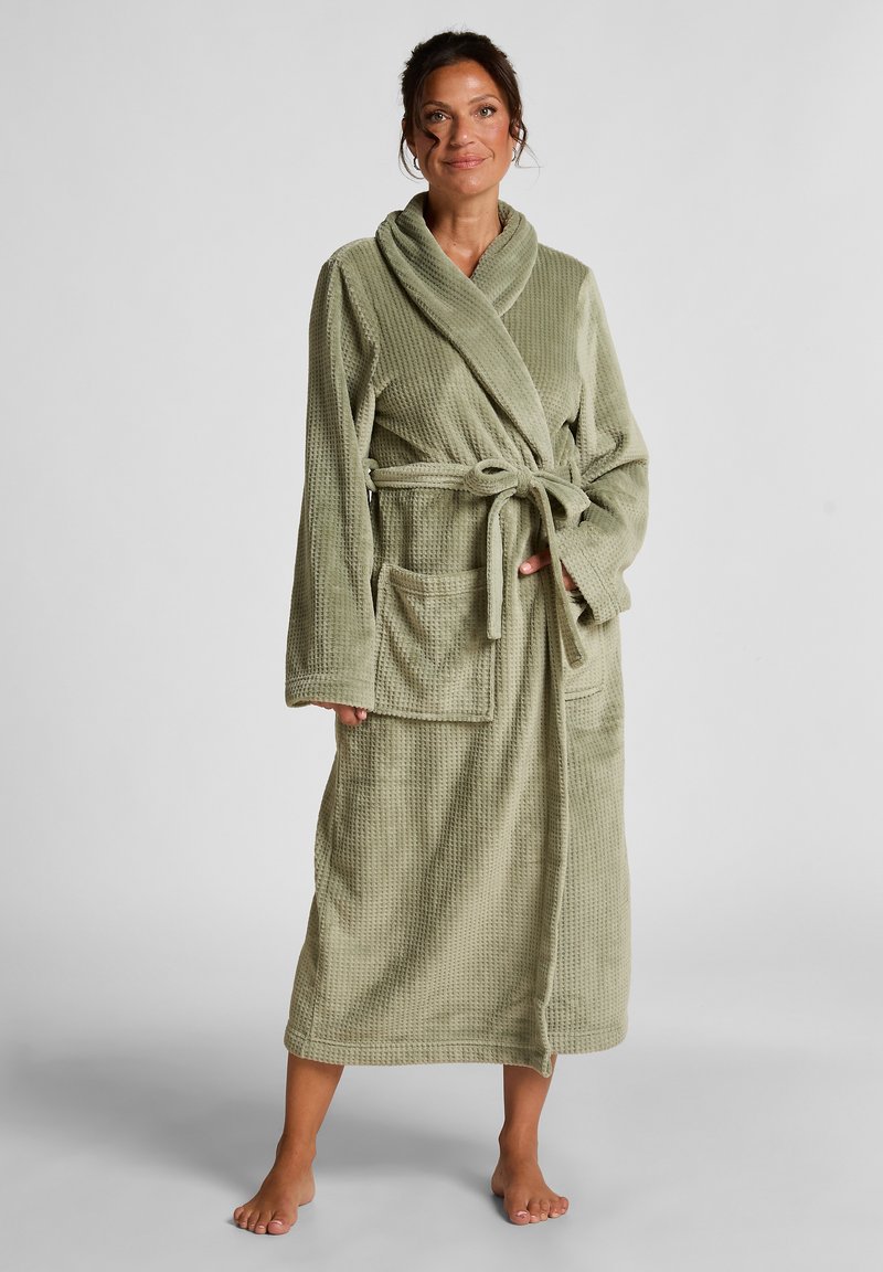 Strikket badekåpe i dempet grønn med teksturert overflate, lange ermer, sjalkrage, to frontlommer og matchende belte.