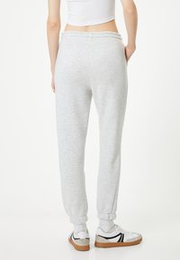 Lys grå sweatpants med elastisk talje og manchetter, der har en glat tekstur og en afslappet pasform. Bæres med casual sneakers.