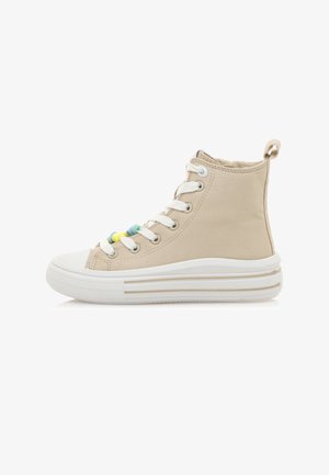 Zapatilla alta de lona beige con suela de goma blanca, que presenta ojales y cordones de colores, detalles texturizados y una pestaña trasera para facilitar su uso.