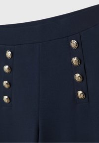Pantalons ajustés bleu marine avec une texture lisse, taille haute et boutons décoratifs en or sur le devant pour le détail.