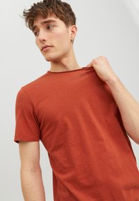 T-shirt a maniche corte color ruggine con un tessuto leggermente testurizzato, caratterizzato da un collo rilassato e una vestibilità ampia.
