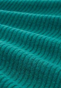 Struktuurne teal-kangas ribade mustriga, millel on pehme, fliisilaadne kvaliteet. Nähtav sügavus ja varieeruv varjund lisavad sellele välimusele. 