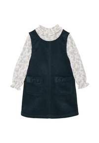 Dunkelgrünes Cordkleid mit Rüschenausschnitt und langen Ärmeln. Weiße Bluse mit leichtem Blumenmuster und zwei frontalen Taschen.