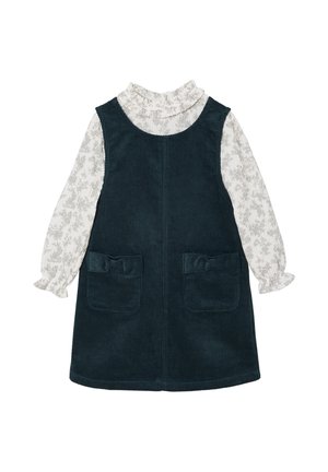 Dark green corduroy dress with ruffled neckline and long sleeves. White blouse features a light floral pattern, with two front pockets.
