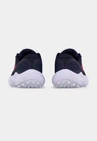 Ζευγάρι ναυτικό μπλε αθλητικά παπούτσια με λευκές σόλες, ορατά από πίσω, με διάτρητα πάνελ στη φτέρνα και ροζ λεπτομέρειες στα πλάγια.