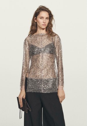 Top trasparente a maniche lunghe con paillettes argentate e nere sparse, con un design di bralette nera solida sotto. Accompagnato da una pochette scura.