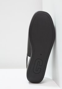 Černá bota s hladkým koženým svrškem, plochou podrážkou, konturovaným tvarem a označenou velikostí 38. Na podrážce se nachází výrazné logo "C".