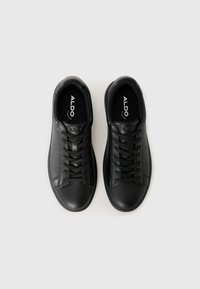 Black leather sneakers with a smooth texture, round toe, and six eyelets for laces. Features branded insole and minimalistic design.