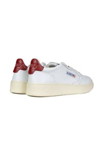 Sneaker bianche in pelle con suola crema texturizzata e accentuazione rossa sul tallone. Presentano lacci piatti e un logo laterale. Design con punta rotonda.