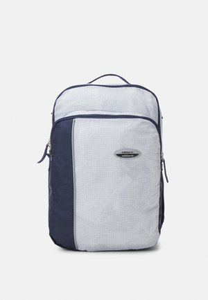 Sac à dos rectangulaire blanc et bleu marine avec petit motif quadrillé, poche avant zippée et logo Adidas sur la poche avant.
