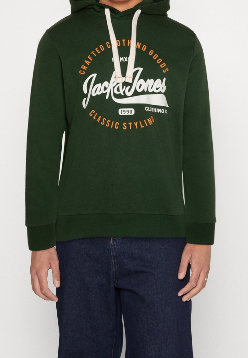 Felpa verde con grafiche frontali, caratterizzata da scritte bianche e arancioni. Coulisse con cappuccio, polsini a costine e vestibilità ampia.