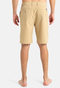 Shorts beiges en tissu léger, avec une taille plate, deux poches arrière à boutons et une coupe droite.